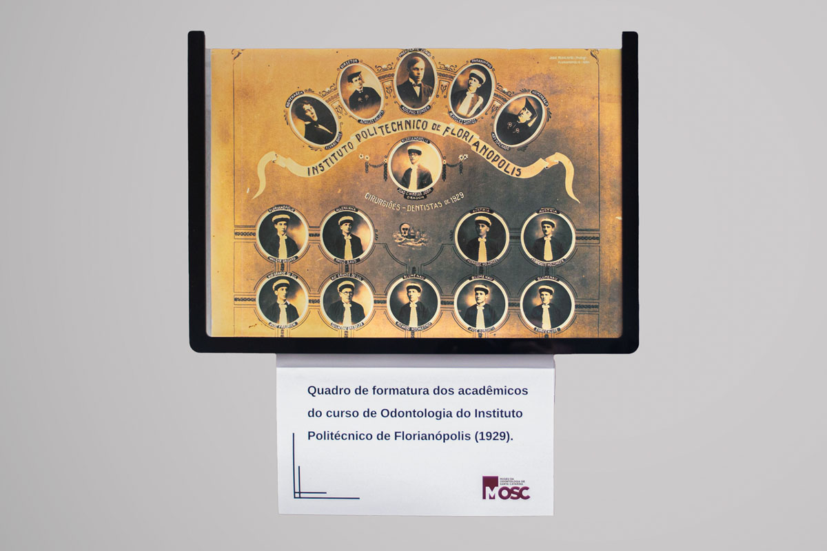 Fotografia de um quadro de formatura do curso de Odontologia do Instituto Politécnico de Florianópolis, datado de 1929. O quadro apresenta retratos individuais dos formandos, dispostos em uma composição simétrica, com os nomes e títulos dos graduados escritos abaixo de cada foto. O fundo é envelhecido, dando um aspecto vintage à peça.